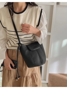 Detail of black lychee grain leather bucket bag with fine stitching and drawstring