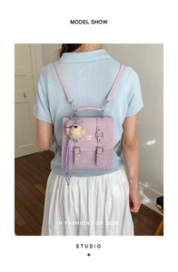 Detail of purple small backpack with bear pendant and silver buckle straps on a model