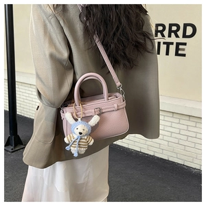 Pink lychee grain leather crossbody bag with a cute sheep plush charm on model back