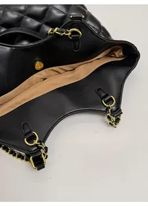 Close-up of black quilted tote bag showing magnetic snap closure and gold chain straps