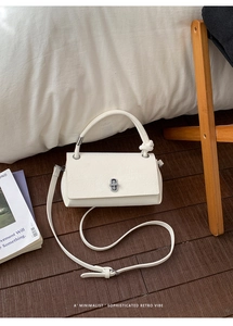 Detail of cream white textured leather handbag with silver lock and knotted handle