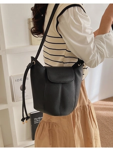 Detail of black lychee grain leather bucket bag with flap closure and drawstring design