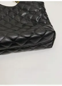 Close-up of the reinforced bottom and diamond quilted leather texture on a black tote bag