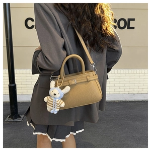 Detail of ginger yellow pebble leather handbag with white plush rabbit charm accessory