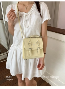 Detail of cream yellow satchel bag with buckle straps and top handle for women
