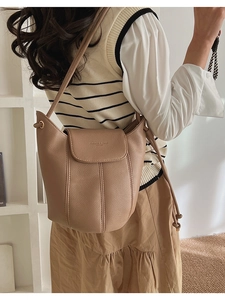Detail view of light brown litchi pattern bucket bag with fine stitching and shoulder strap