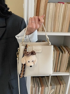 Chic beige lychee grain bucket bag with plush puppy charm and tassel shown by model