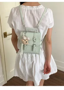 Detail of mint green mini leather backpack with plush bear charm and buckle straps