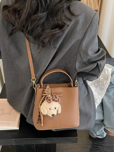 Brown litchi grain bucket bag with plush charm and detachable shoulder strap