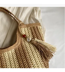 Detail of the woven paper straw texture and side tassel with decorative beads on a bag