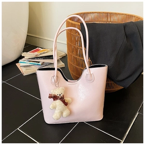 Detail of pink glossy patent leather tote bag with a cute white teddy bear charm
