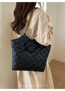 Detail of black quilted tote bag featuring gold chain and leather patchwork straps