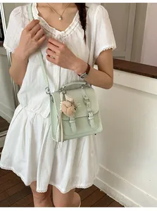 Detail of mint green matte leather messenger bag with cute plush bear and silver buckle