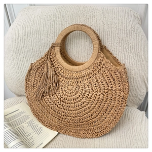 Détail d'un sac de plage en paille tissé à la main avec poignées rondes et glands