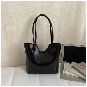 Detail of black glossy oil wax leather tote bag with wavy top edge and thin straps
