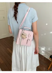 Pink square flap bag with silver buckles and a cute teddy bear charm on the back