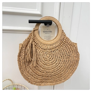 Détail d'un sac à main en paille tressée avec un design en demi-lune et des franges