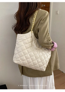 Detail of off-white quilted tote bag with golden metal chain shoulder strap and PU leather
