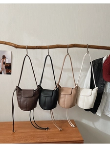 Litchi pattern leather bucket bags in four colors hanging on a wooden display stand