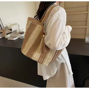 Vue détaillée du sac à bandoulière en paille tressée avec pompons décoratifs en perles de bois et texture