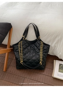 Detail of large black quilted tote bag with gold chain and refined leather texture