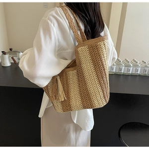 Détail d'un sac cabas en paille tissé à la main avec rayures brunes et longues franges