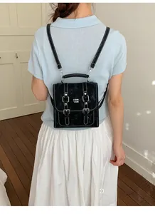 Detail of black backpack with white contrast stitching and silver buckle on model