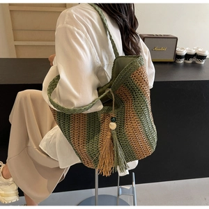 Détail du sac cabas tissé à rayures vertes et beige avec pompons bohèmes et poignées