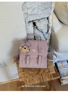 Detail of lavender matte backpack with double buckles and a plaid bow bear charm