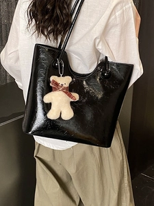 Chic black patent leather tote bag with plush bear charm for stylish daily commuting