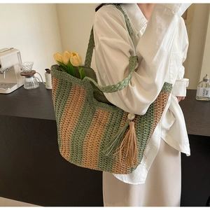 Détail du sac cabas en paille à rayures vertes et bēiges avec pampilles et perle blanche