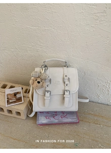 Detailed view of a white minimalist backpack with aesthetic bear charm on a studio setup