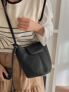 Chic black lychee grain leather bucket bag shown as a stylish crossbody bag on a model