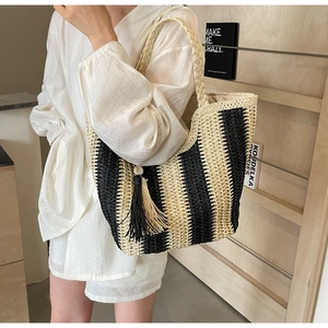 Détails du sac cabas en paille tissée avec rayures bicolores et pompons noirs