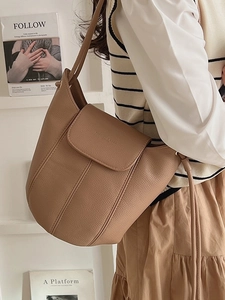 Brown lychee texture leather bucket bag shown on model with shoulder strap in studio