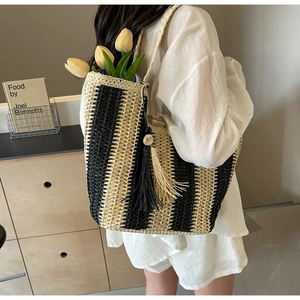 Détail d'un sac cabas tissé à rayures avec glands sur un mannequin en intérieur