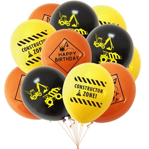 Close-up of construction party balloons in yellow, orange, and black with excavator patterns