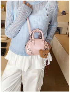 Pink shell handbag with silver rivets and cute bear charm shown in a side view on model