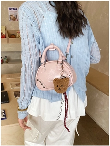 Pink shell handbag detail with metal studs, faux leather texture and a plush bear charm