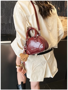 Detail of red brown shell handbag with silver studs and cute bear charm accessory