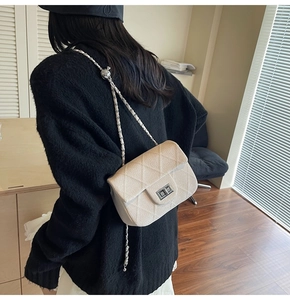 Rear view of a beige quilted crossbody bag with a silver chain strap and metal lock