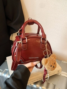 Fashionable wine red shell handbag with bear pendant and adjustable shoulder strap