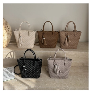 Détail de sacs seaux tressés en cinq couleurs avec glands sur un support de présentation
