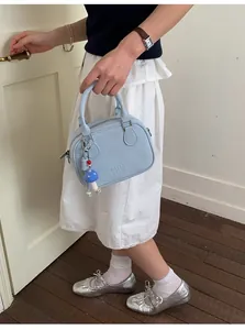 Détail du mini sac Boston bleu clair avec charm champignon et logo embossé