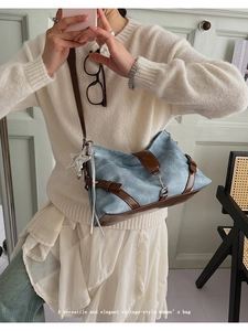 Detail of light blue denim baguette bag featuring brown leather trim and star charm