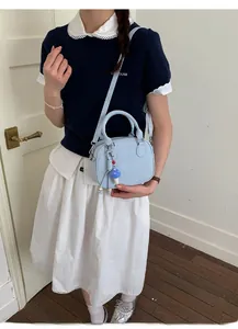 Détail du sac à bandoulière bleu clair avec lettres embossées et charm champignon à pois