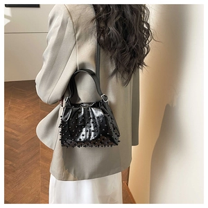 Fashionable black beaded bucket bag styled on a beige blazer for an elegant commute look