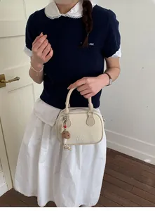 Détail du sac cylindre en cuir crème avec logo MUTING et accessoire charm champignon