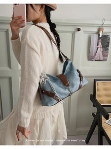 Close-up of denim underarm bag with brown leather trim and silver star pendant