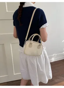 Détail d'un mini sac en cuir blanc crème avec logo MUTING embossé et doubles poignées